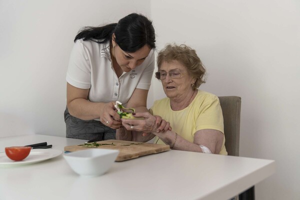 Пациентка со слабостью в руке на занятии с эрготерапевтом учится чистить овощи