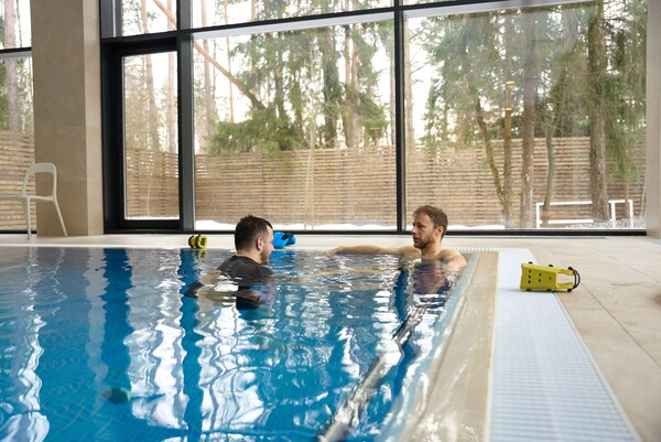 Пациент занимается с акватерапевтом в бассейне во время реабилитации