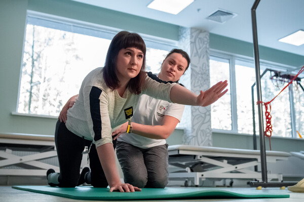 Пациентка выполняет упражнение на баланс вместе с физическим терапевтом