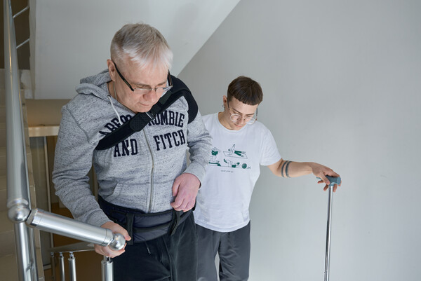 Пациент отрабатывает подъём по лестнице на занятии с физическим терапевтом
