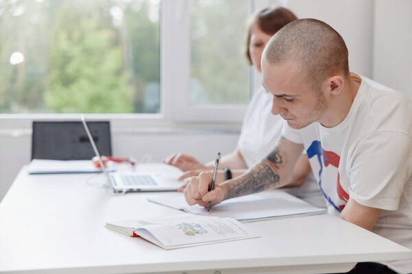 Пациент учится писать после спинальной травмы на занятии с эрготерапевтом