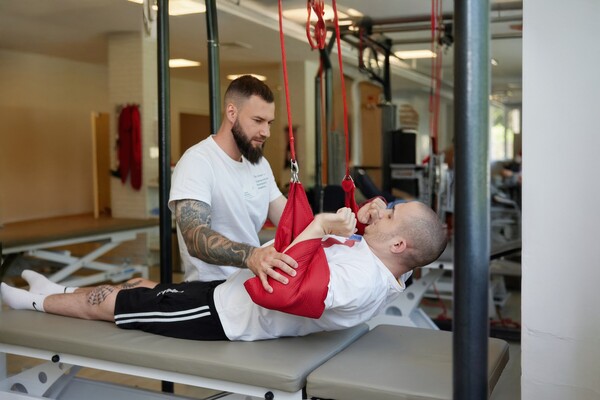 Пациент со спинальной травмой занимается с физическим терапевтом в подвесной системе Экзарта